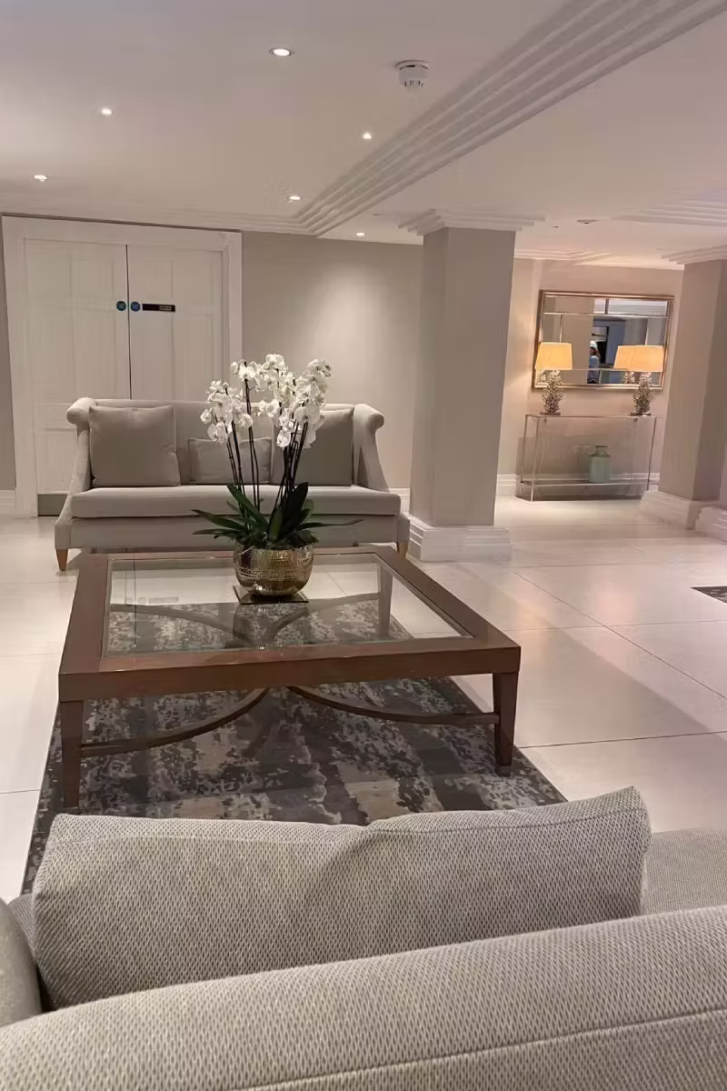 Elegant lounge interior with cream sofas, a glass-top coffee table, and white orchids.