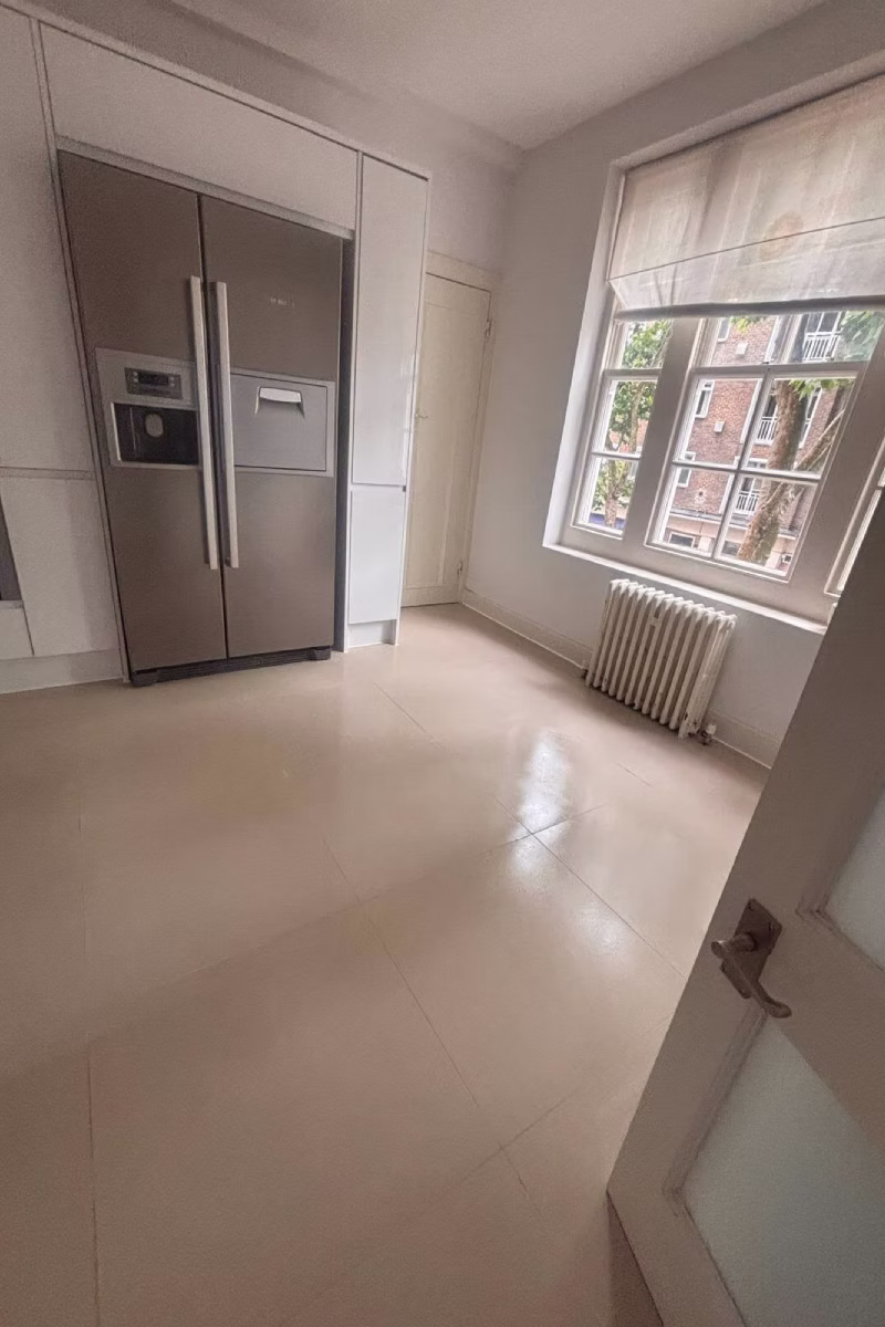 Kitchen with stainless steel double-door refrigerator, cream tiled floor, and a large window.